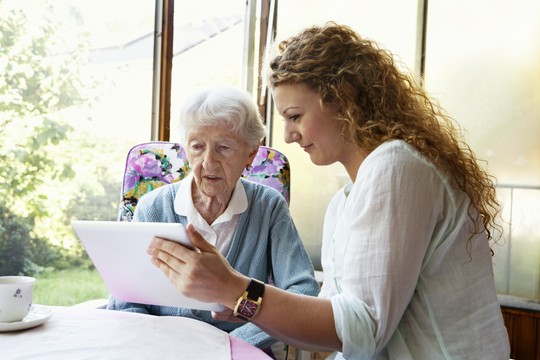 opiekunka i seniorka oglądają coś na tablecie